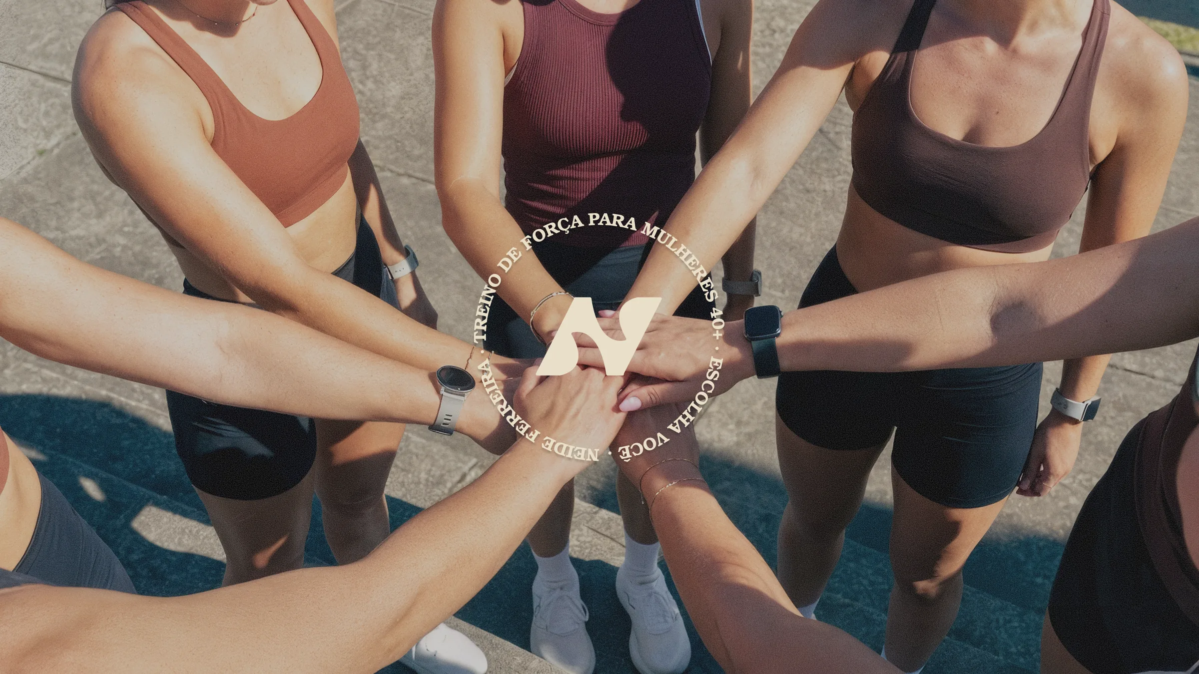 Grupo de mulheres com as mãos unidas ao centro, selo da marca sobreposto.